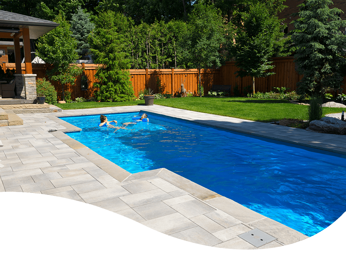 Two people swimming in their backyard swimming pool.